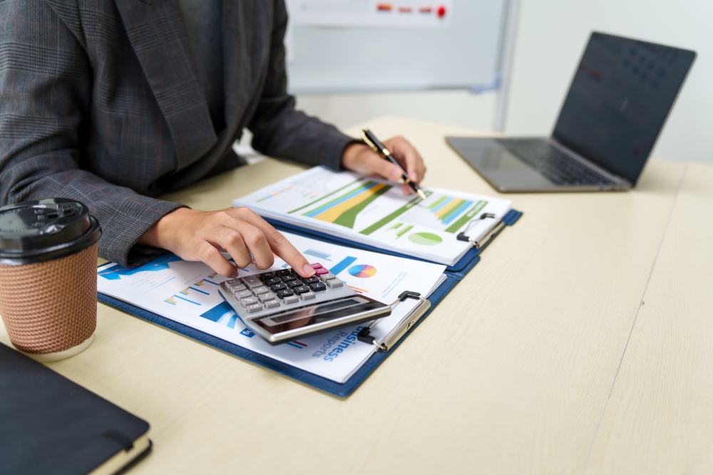 Person calculating with documents and laptop